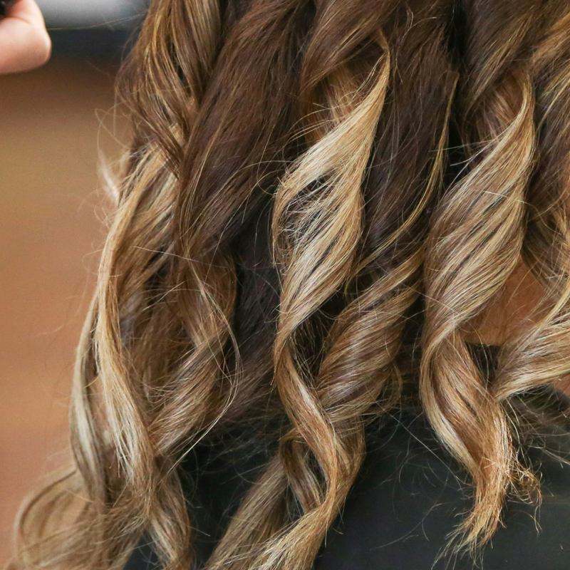 Melena larga con ondas definidas y mechas rubias sobre base castaña