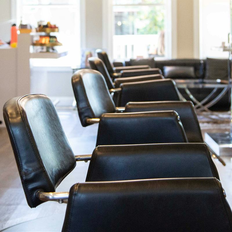Fila de sillones negros del salón junto a un gran ventanal