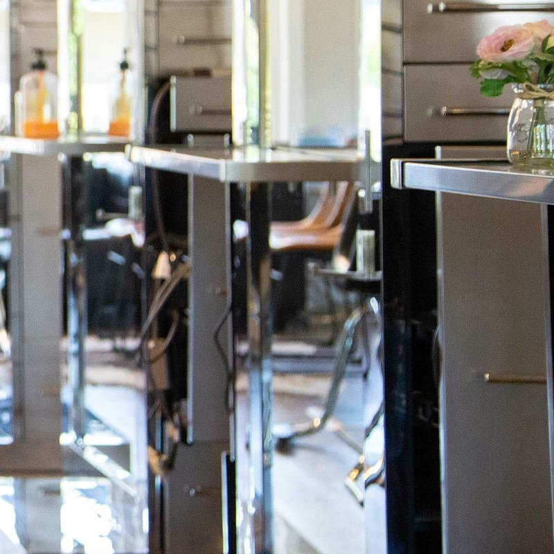 Tocadores del salón con espejos y un jarrón de flores rosas
